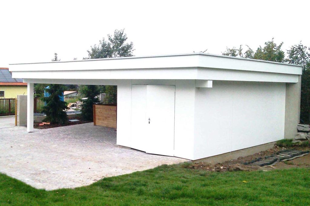 Carport aus Holz mit Flachdach und angebautem weißem Geräteraum neben einer gepflasterten Einfahrt