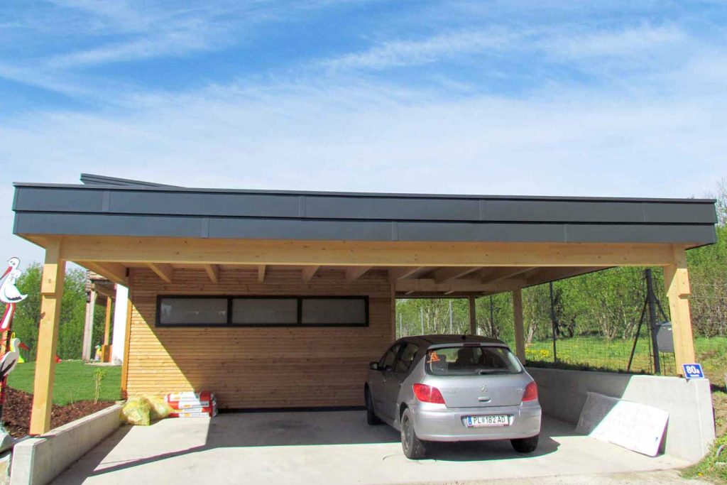 Doppelcarport aus Holz mit Flachdach und Holzverkleidung an der Rückwand, darunter ein parkendes Auto