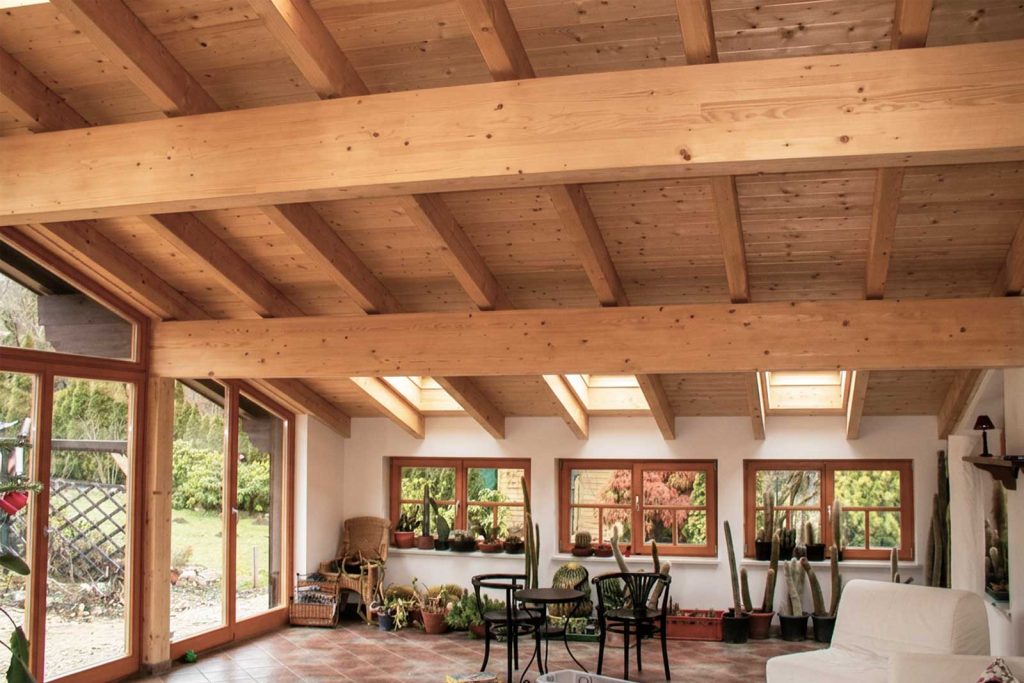 Fertig ausgebauter Dachraum mit sichtbaren Holzbalken, Dachfenstern und Glasfront